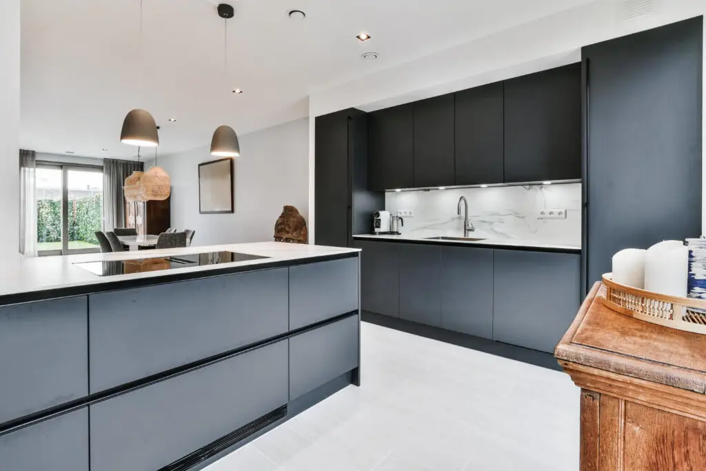 Cuisine contemporaine noire et blanche avec éclairage suspendu.